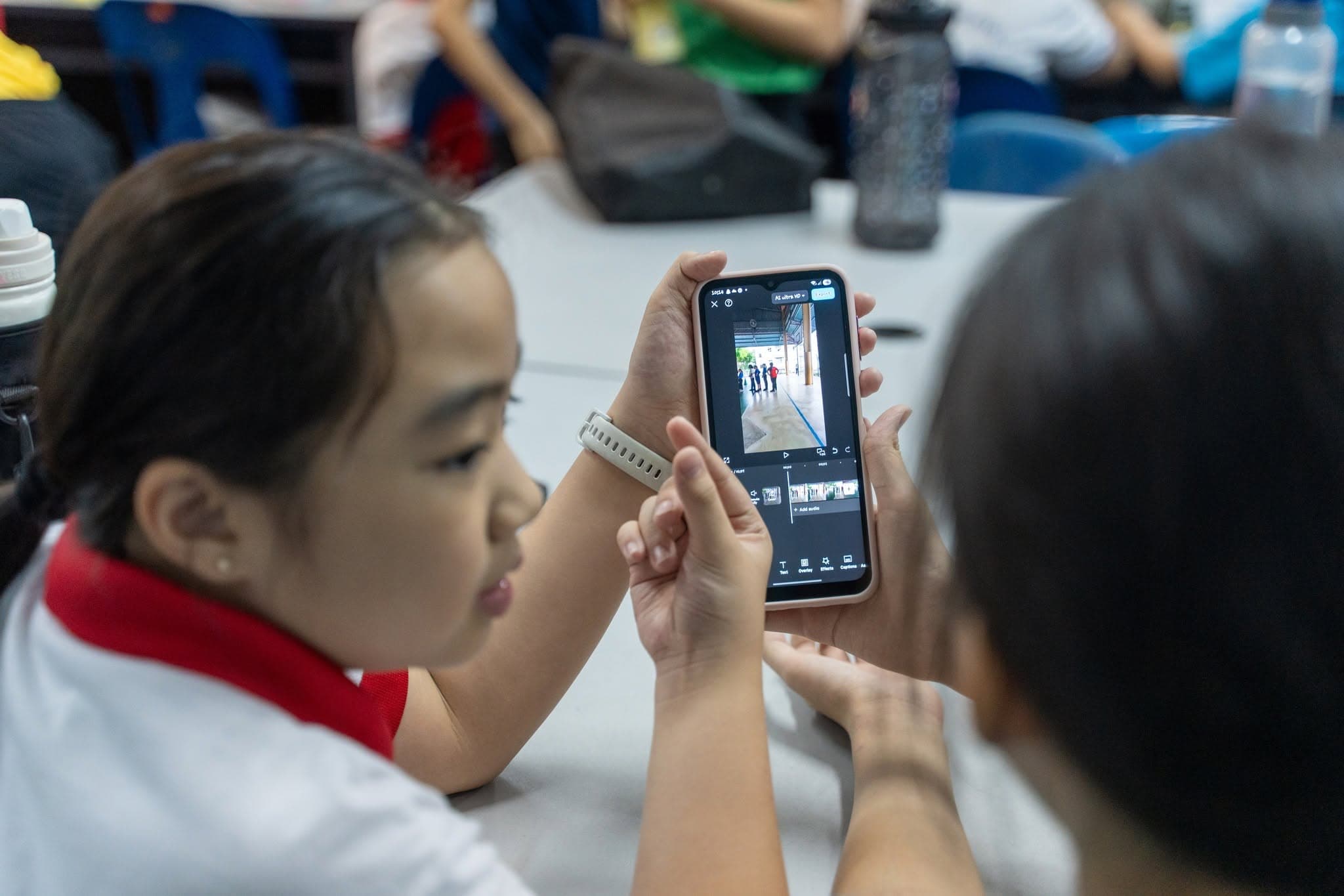 Students exploring video editing on a mobile phone.